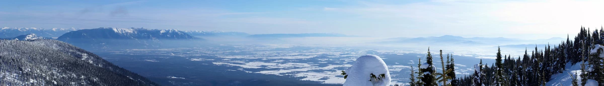 Winter panorama from Whitefish Mountain with snow-covered trees and distant mountains